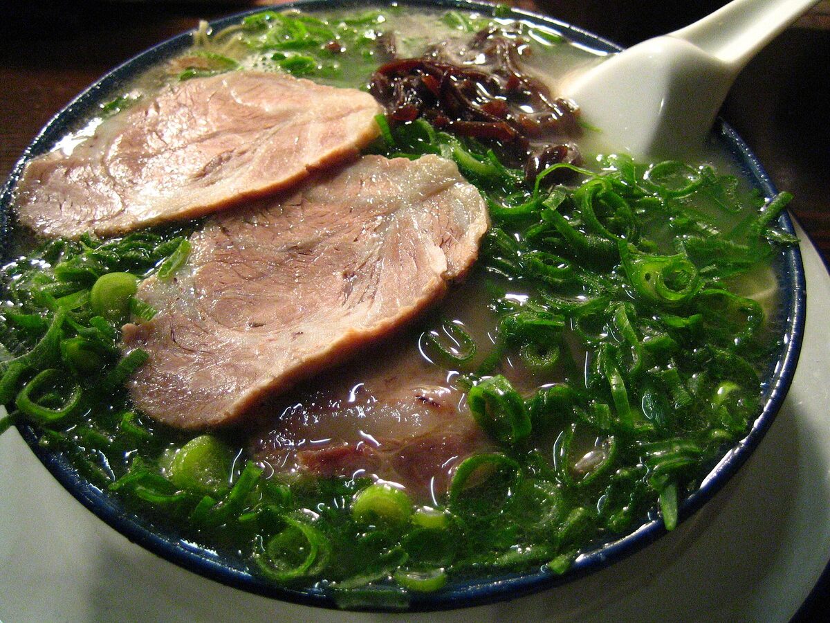 Una ciotola di ramen Hakata con noodles sottili, brodo di maiale e cipollotto verde