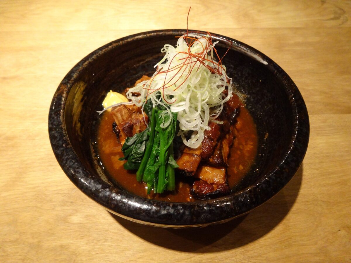 Una porzione di tonkotsu di Kagoshima preparata con maiale kurobuta e servita in una ciotola scura