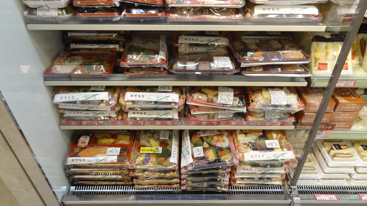 File ordinate di bento confezionati esposti sullo scaffale refrigerato di un konbini